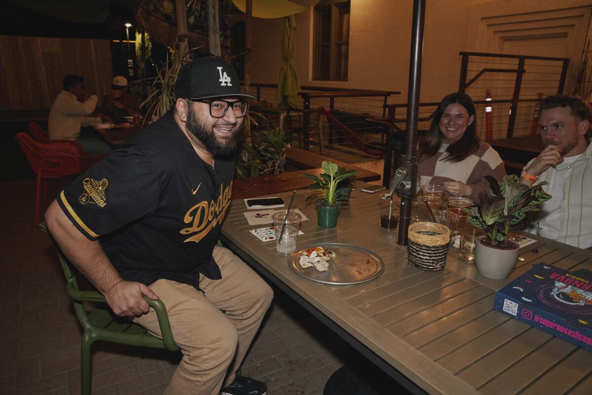 A laughing man sits at a table near a plant he just won.
