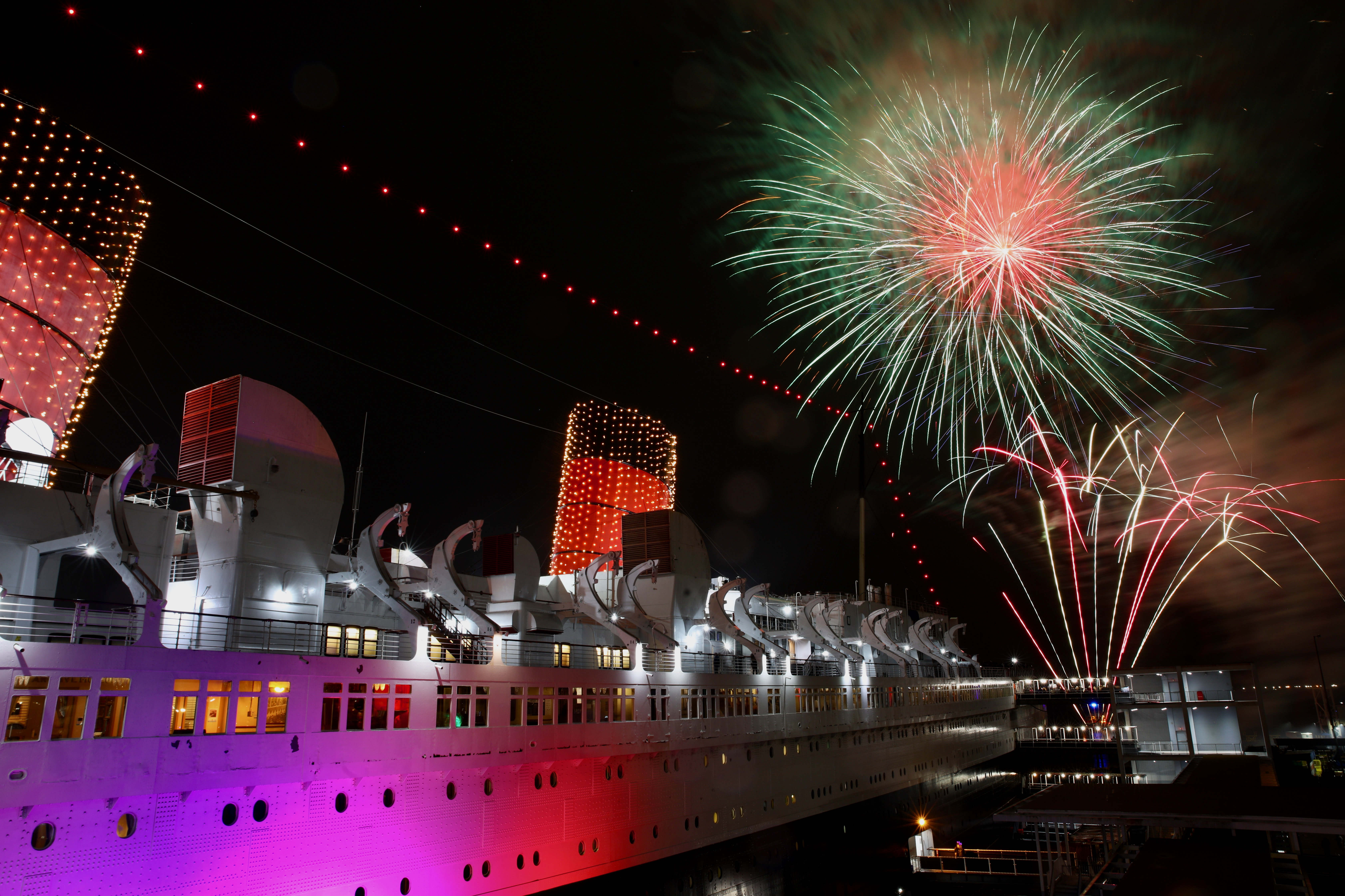 Fireworks light the sky over the Long Beach harbor at...