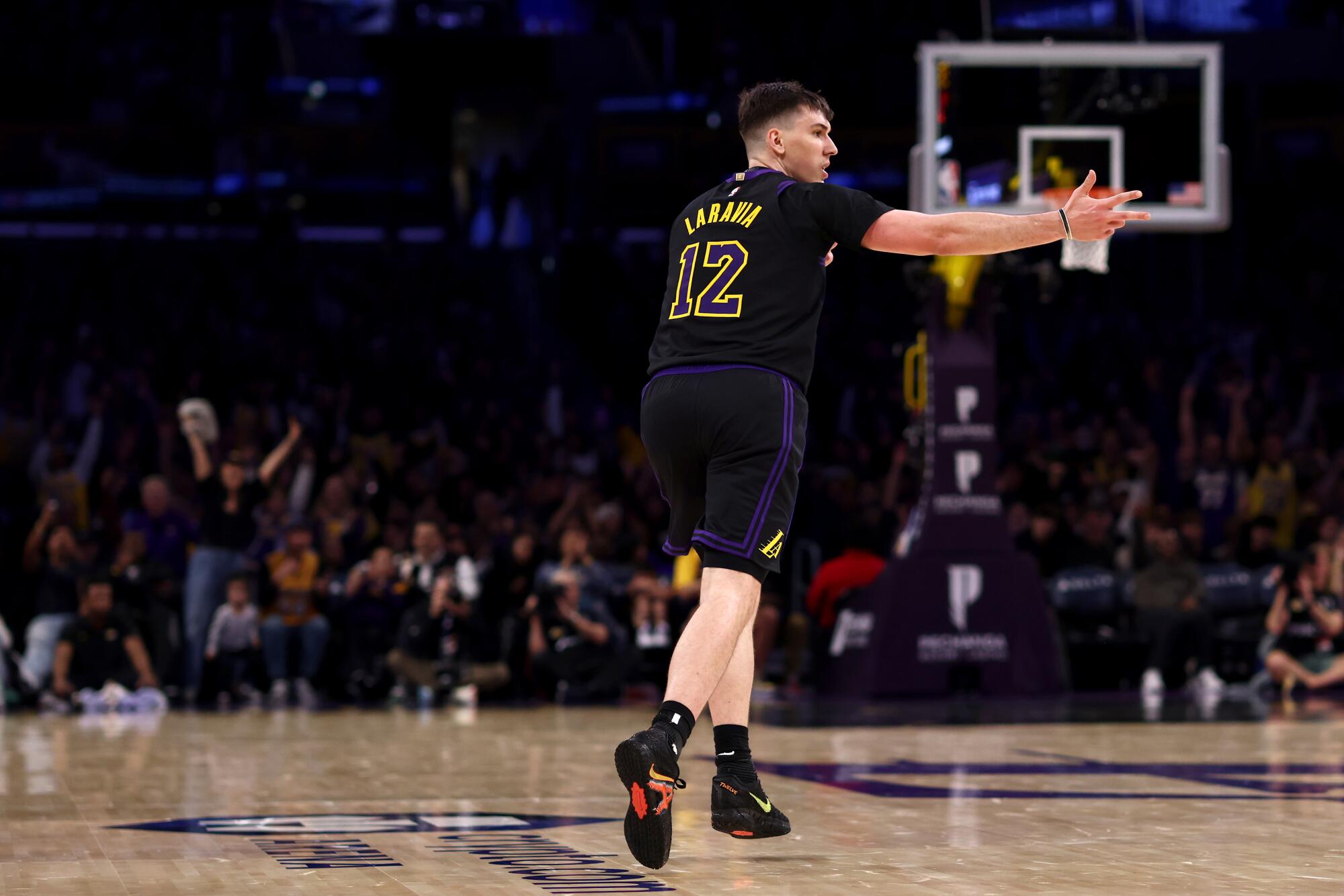 Laker Jake LaRavia extends his arm as he celebrates making a three-pointer while running up court.