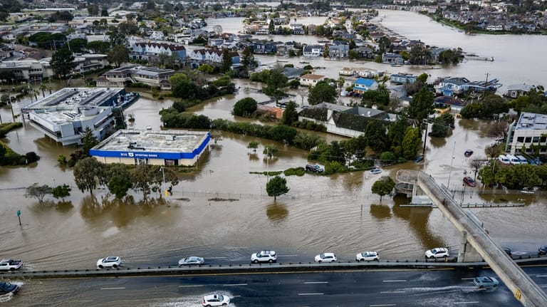 Cars drive on highway 101 flooded by the king tides,...