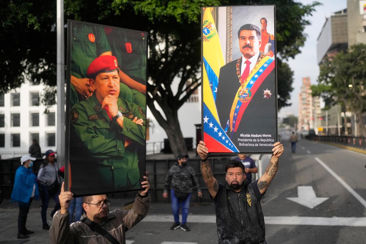 People hold up posters of Nicolás Maduro and Hugo Chávez