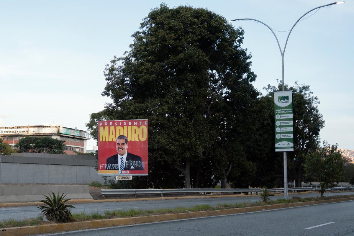 A billboard with an image of President Nicolas Maduro and spray-painted graffiti.