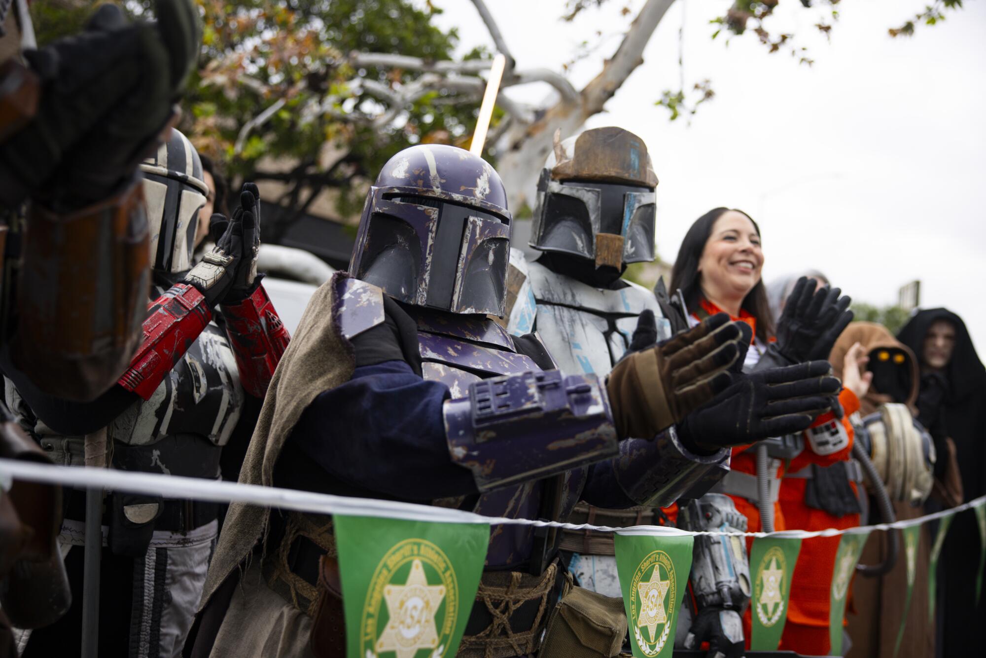 People in Mandalorian costumes cheer.