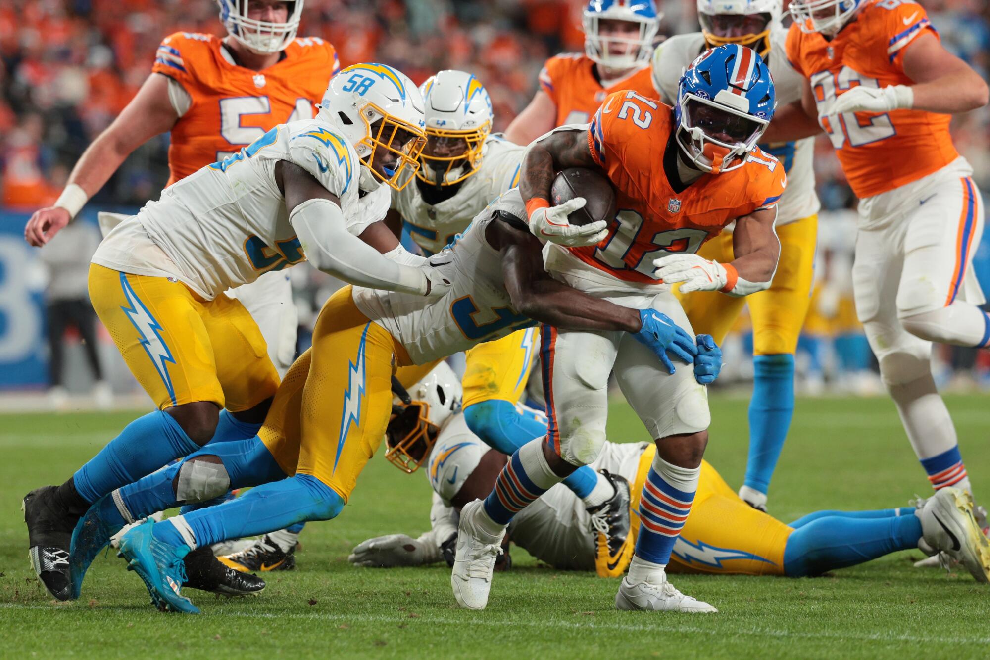 Denver running back RJ Harvey is tackled by Chargers defenders during the second half Sunday.