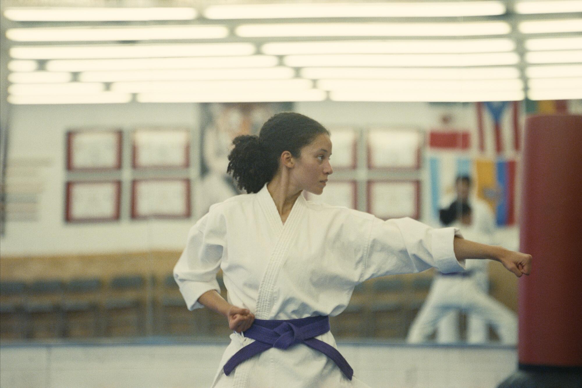 A young woman practices karate in a dojo.