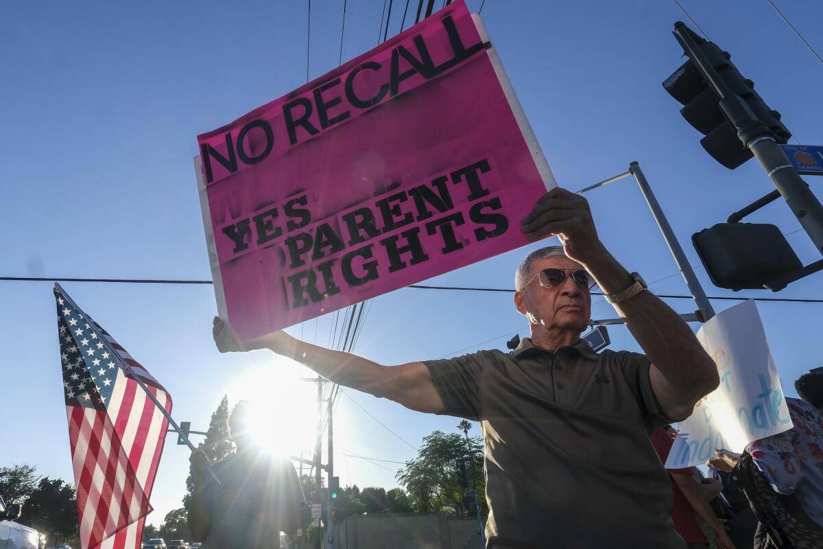 A man holds sign in support of parents rights outside a school board meeting.