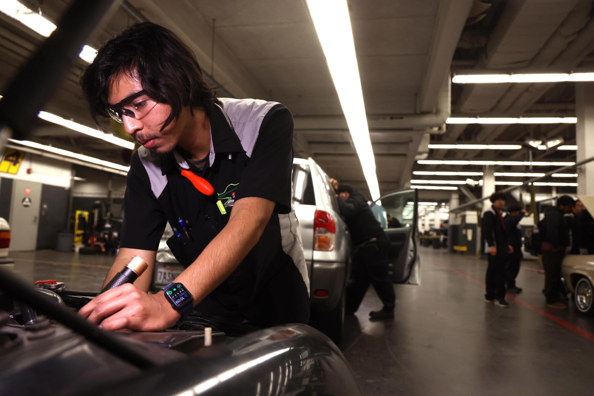 A person looks under the hood of a car.