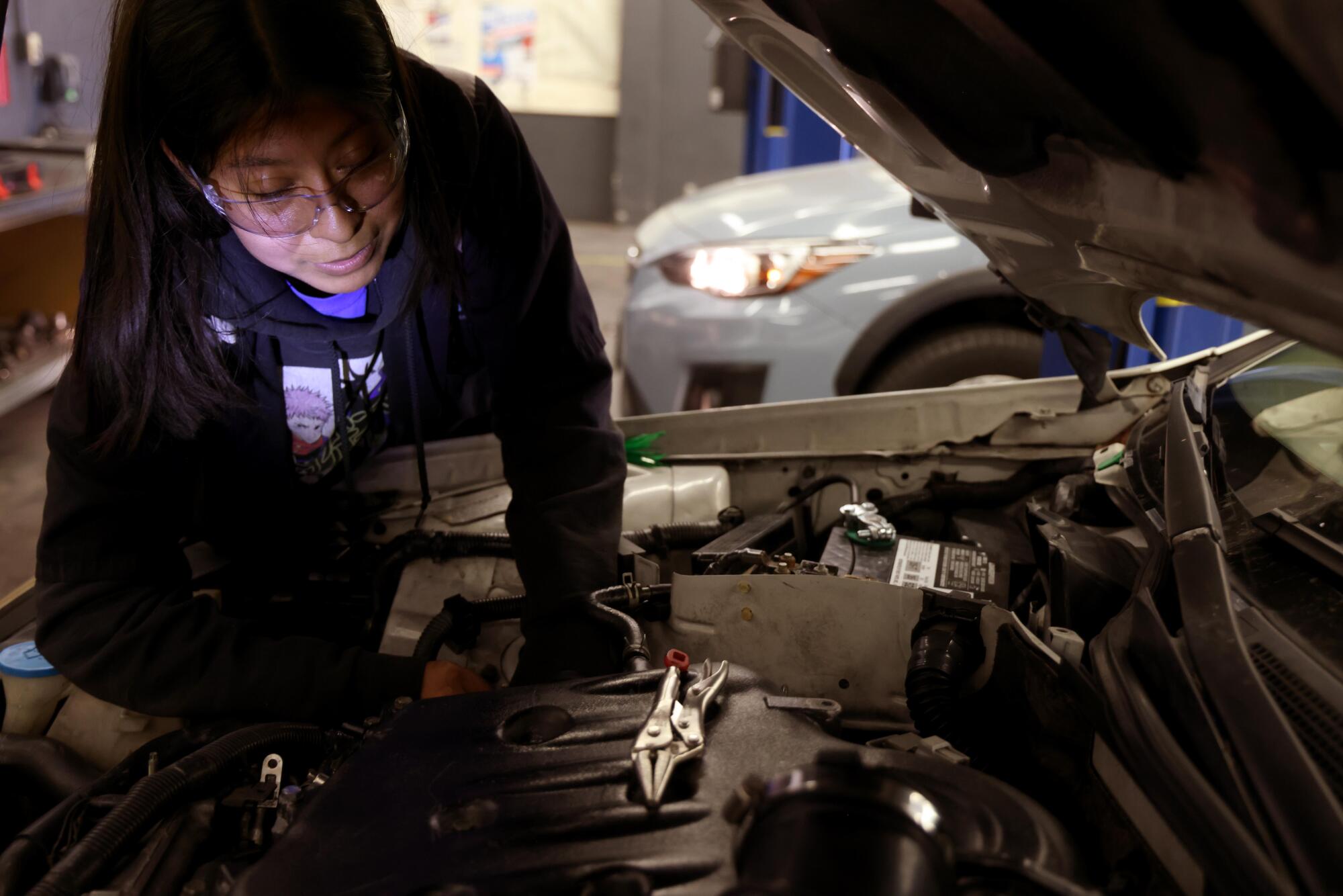 A person leans under the hood of car.