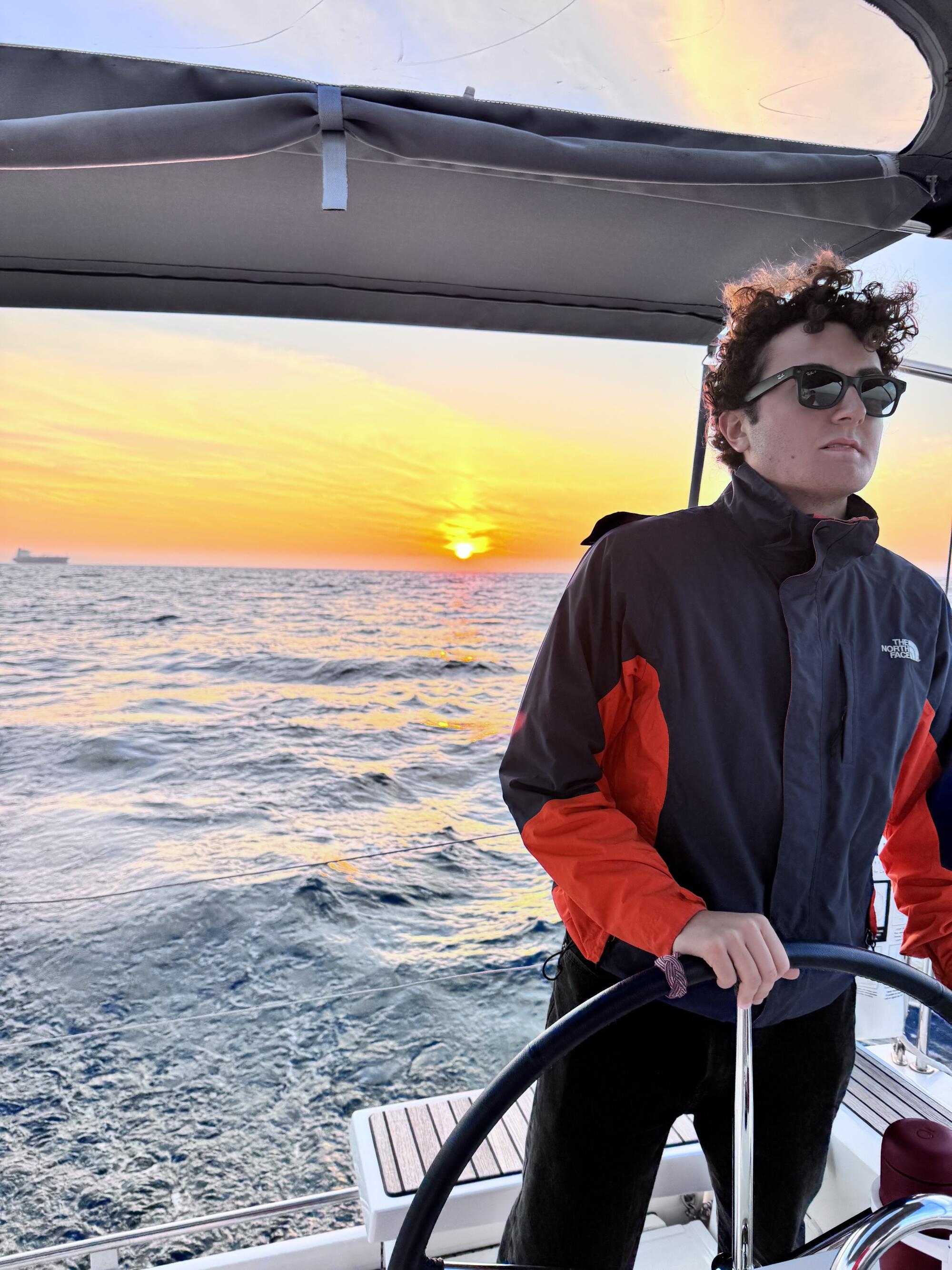 A man steers a wheel on a boat in the ocean.