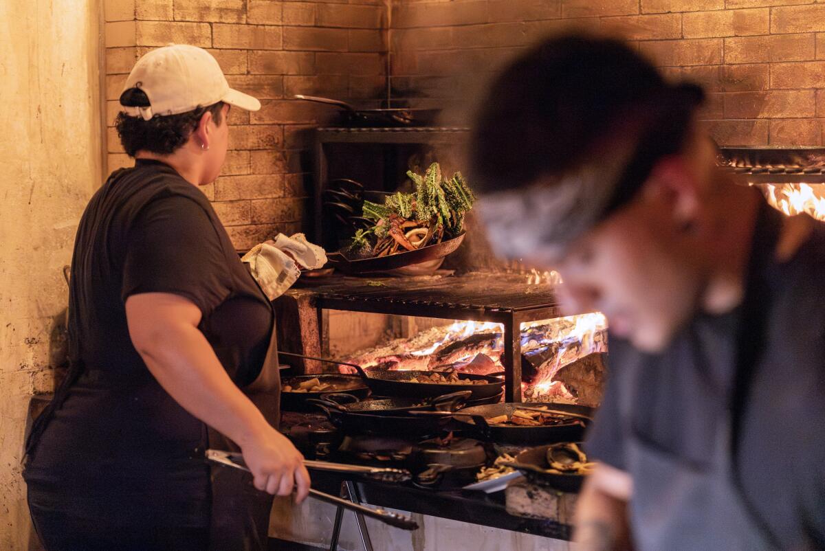 Cooks prepare dishes at Betsy’s central wood-fired hearth.