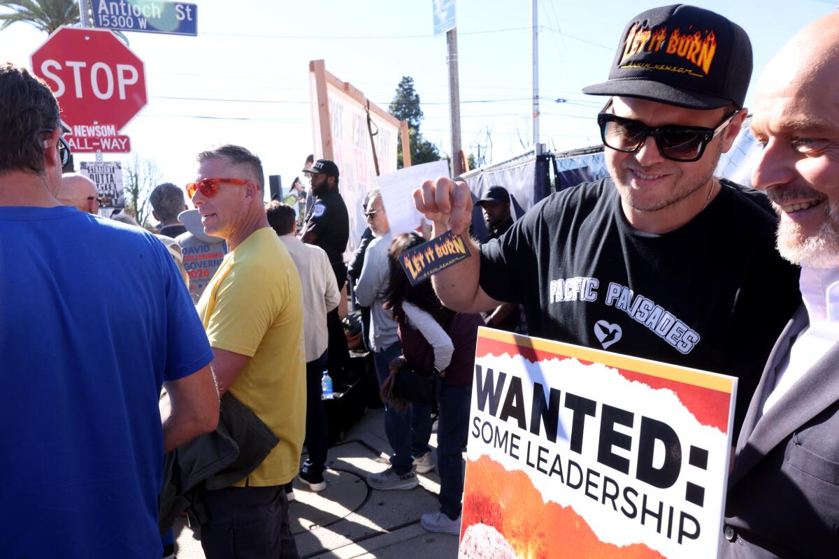 Palisades resident Spencer Pratt with another man holding a sign saying wanted: some leadership.