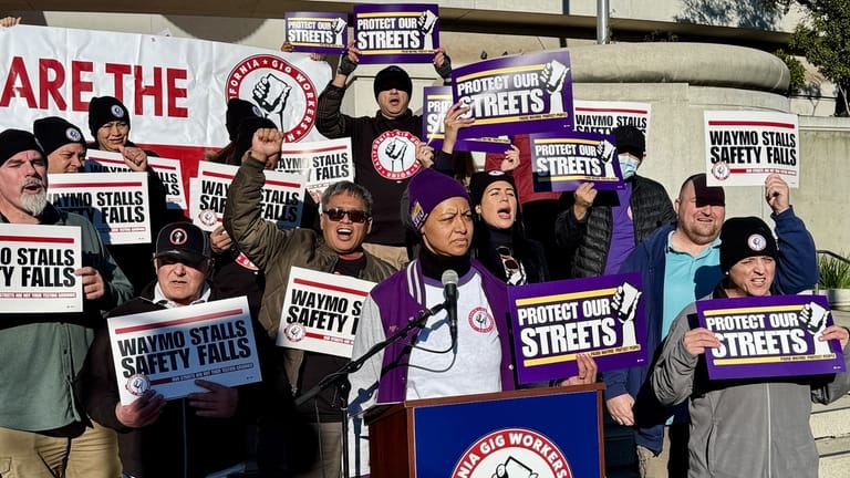 Demonstrators holds signs during a protest by Uber and Lyft...