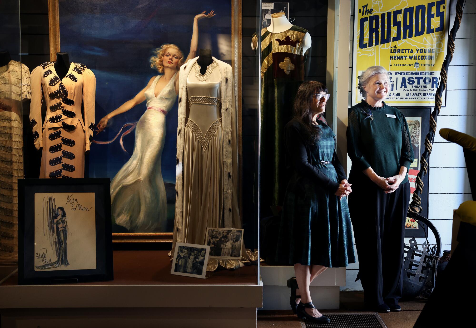 Margot Gerber and Angie Schneider stand next to museum costume displays.
