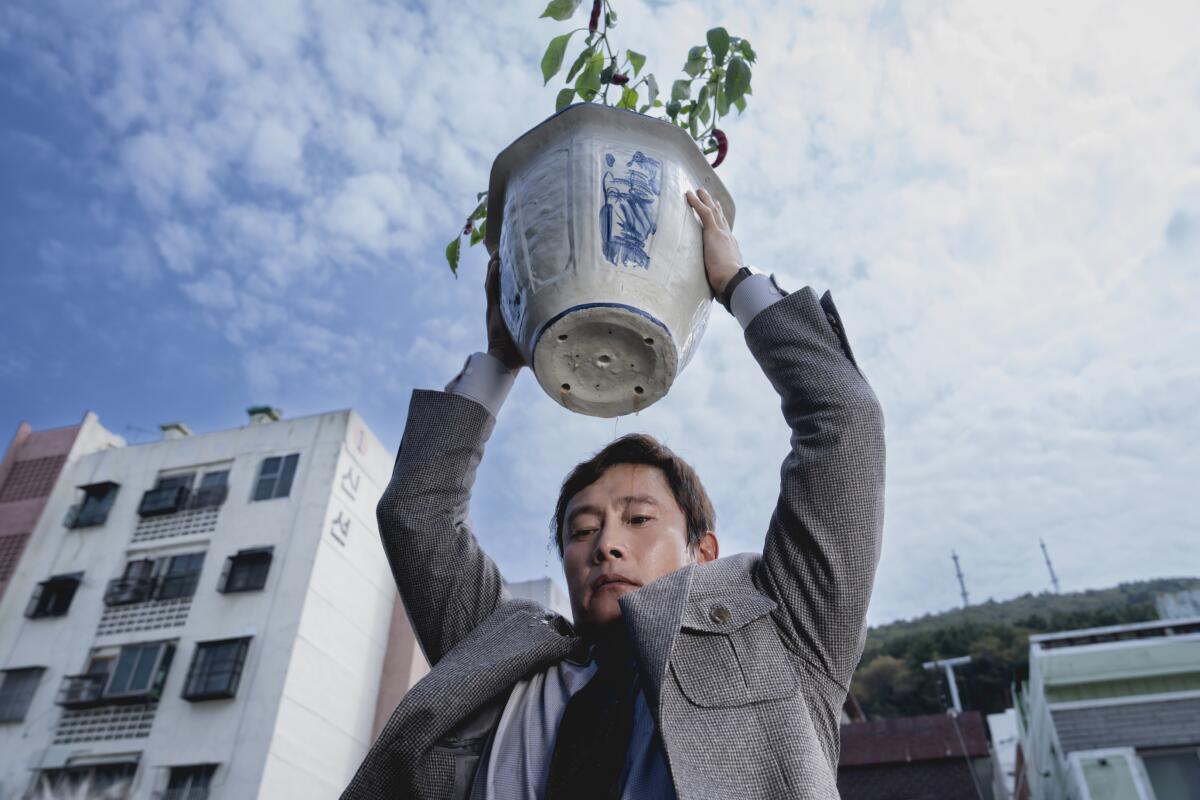 A man raises a flower pot ominously.