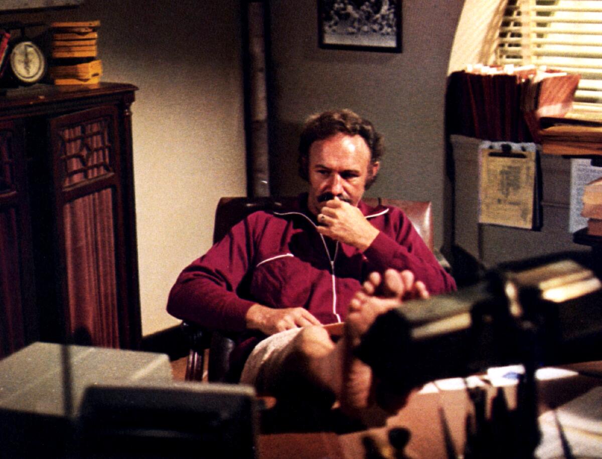 A man sits in his living room with his feet up, thinking.