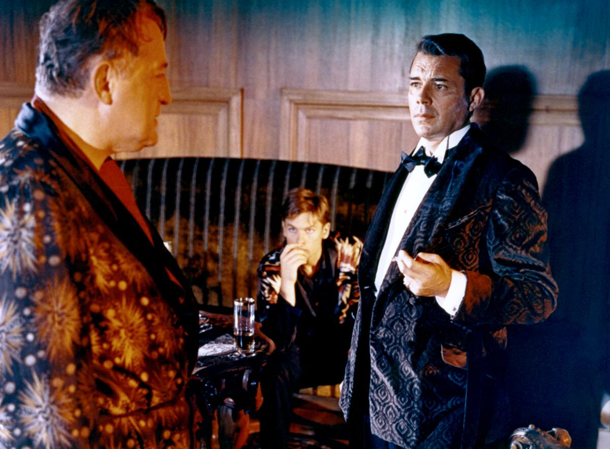 Three wealthy men have a conversation in a drawing room.