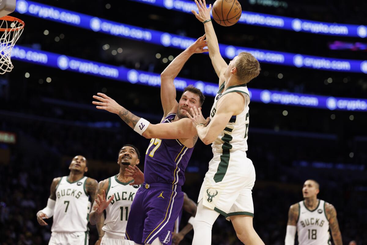 Lakers guard Luka Doncic, center, makes a backwards pass over Bucks guard AJ Green (20) during the first half Friday.