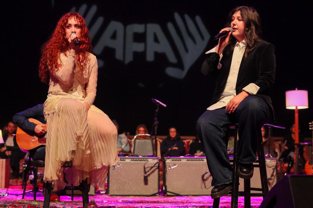 Chappell Roan, left and Lucy Dacus, right perform onstage during Artist for Aid benefit concert at Shrine Auditorium.