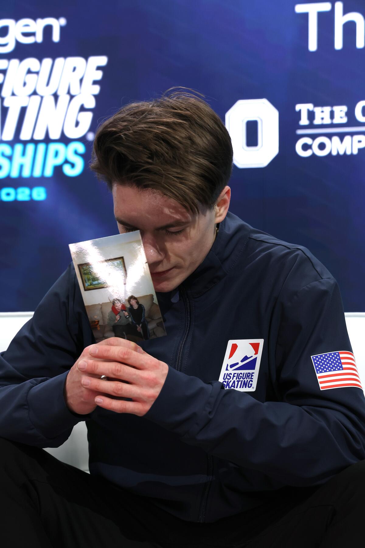 Maxim Naumov holds a photograph of his parents, kissing it while fighting back tears while he waits to hear scores.