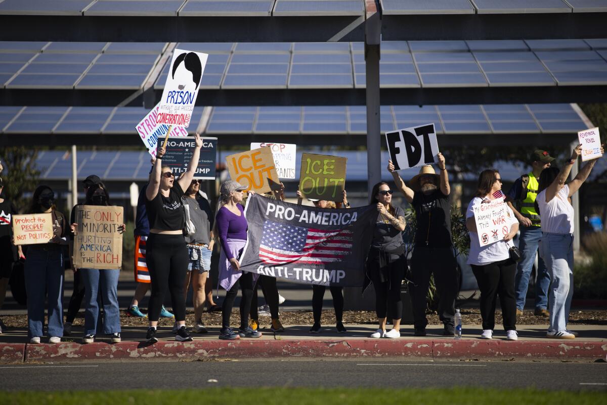 People hold up signs including "ICE Out" and "Pro-America, Anti-Trump."