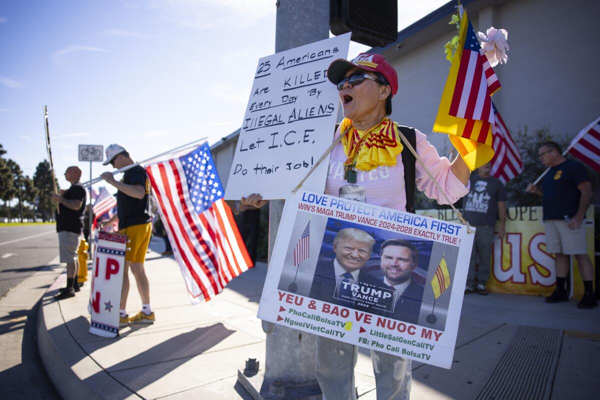 A handful of people hold American flags and signs.