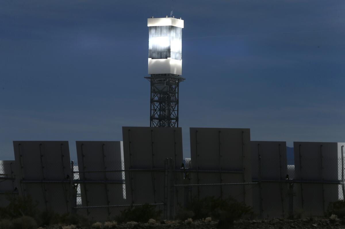 A tower rises above panels, its surface reflecting the sun.