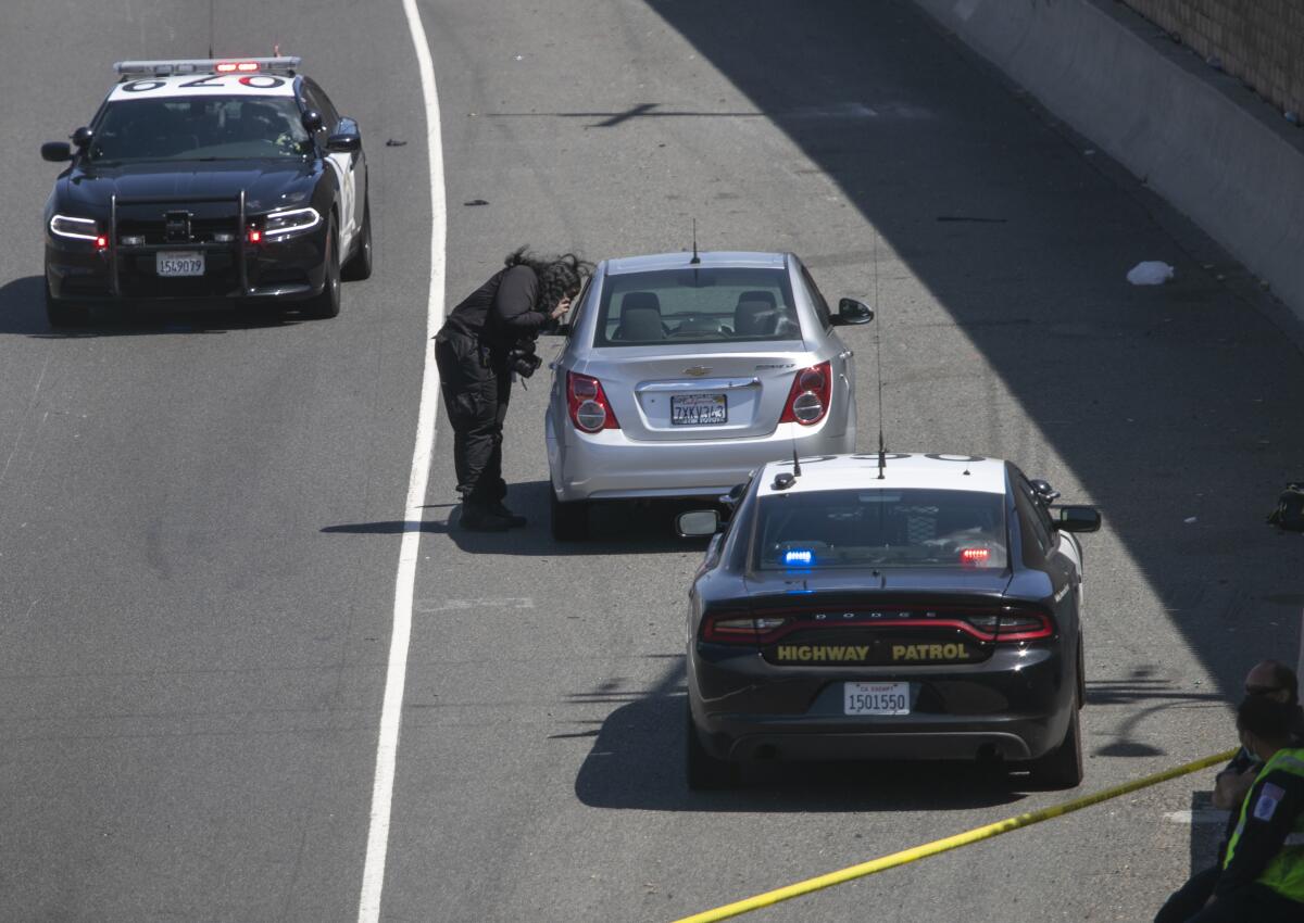 CSI investigator photographing car with a bullet hole in the hatch on the the northbound lanes of the 55 Freeway.