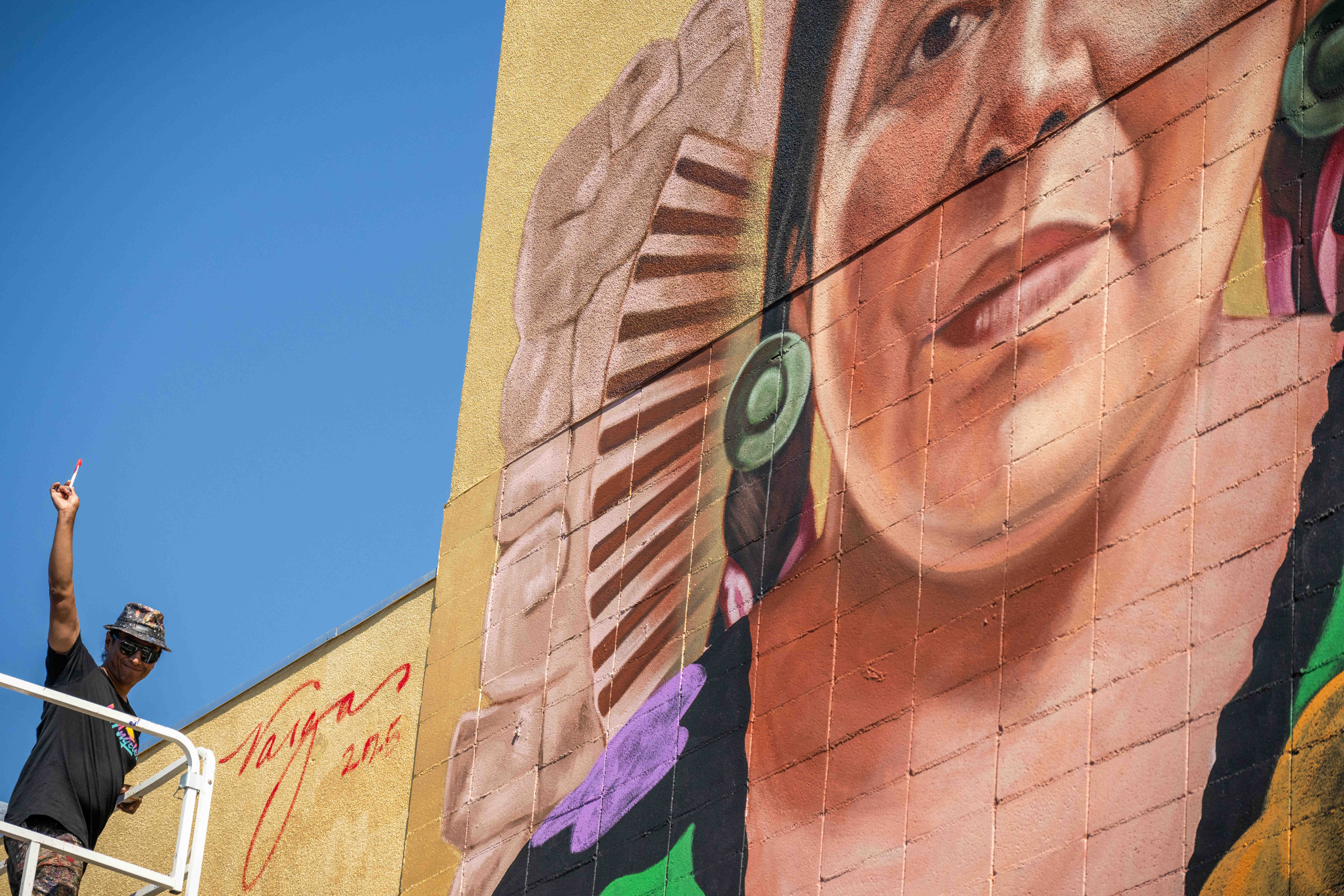 Artist Robert Vargas signs his âNourishing the Communityâ mural depicting...