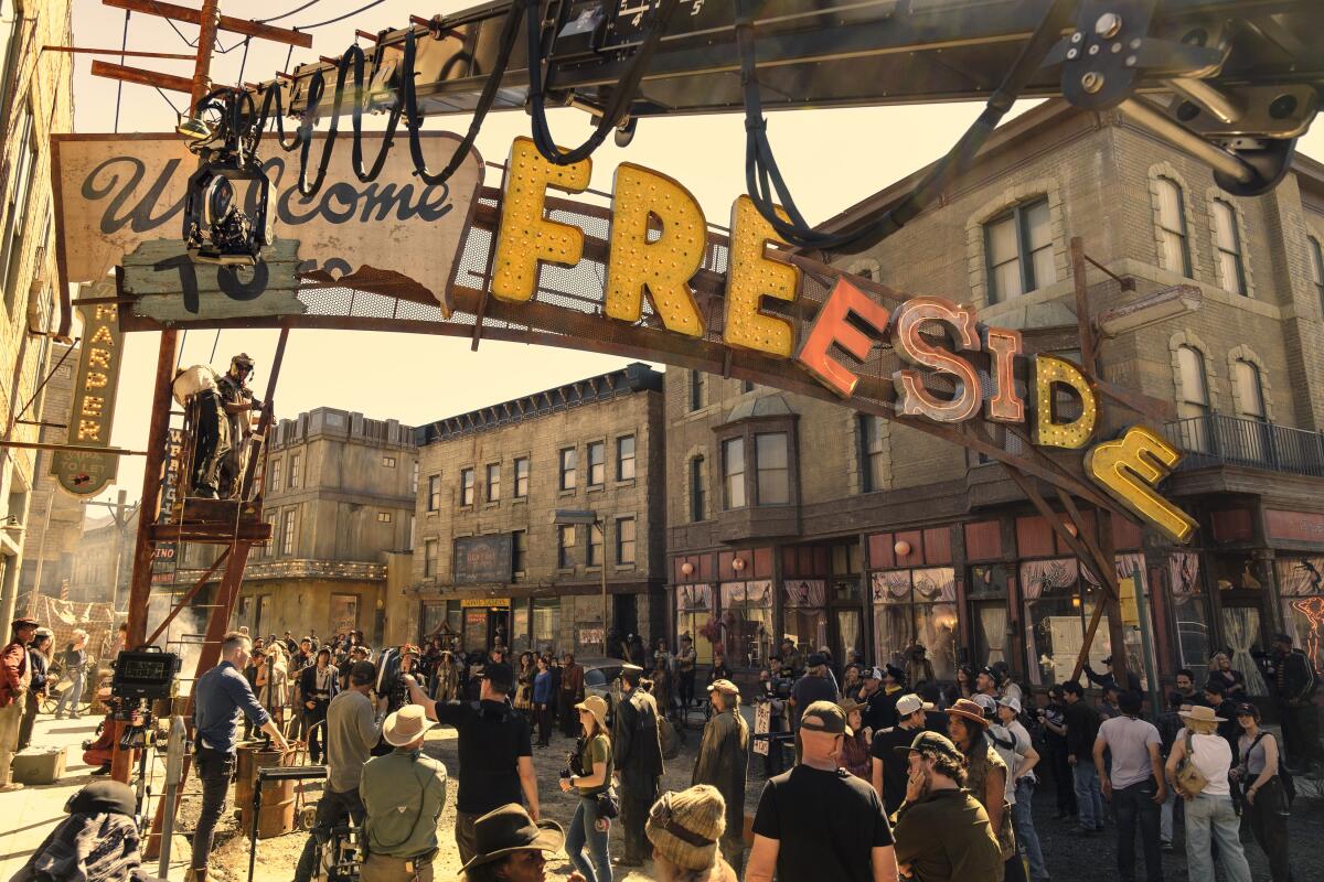 a group of people gathered on a dirt road on a film set