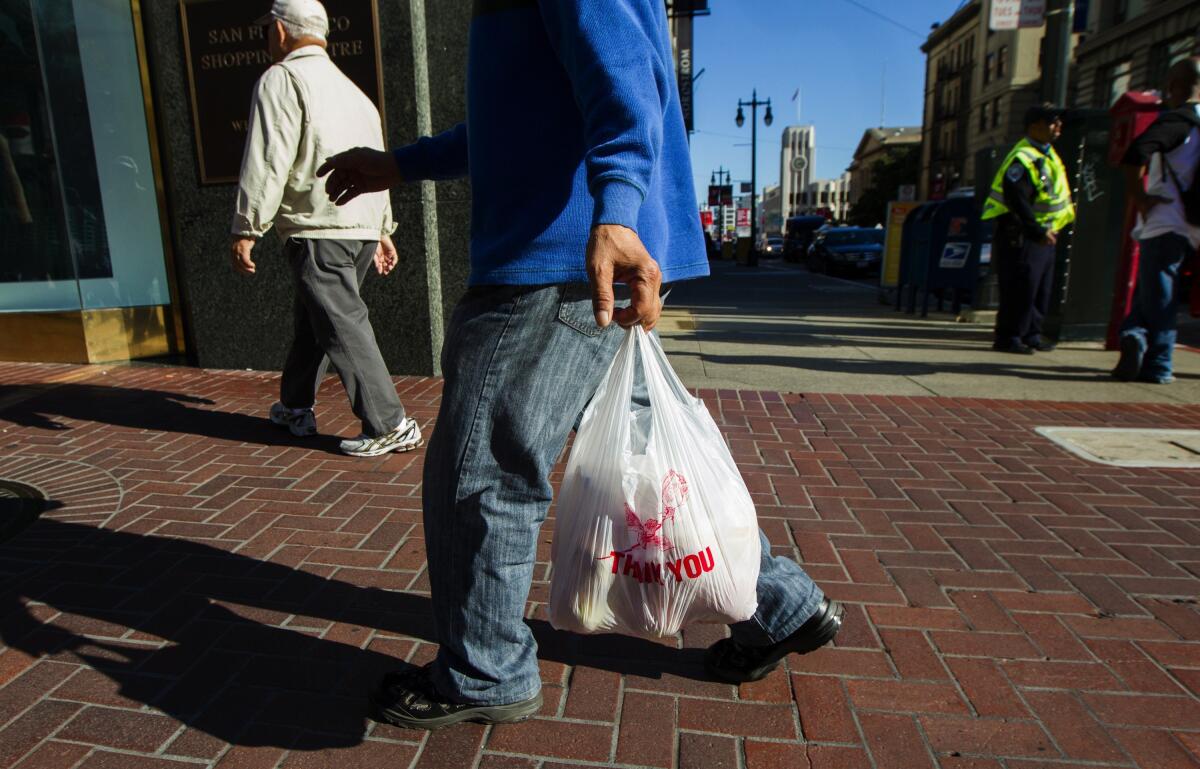 A man carries a single-use plastic bag in San Francisco.