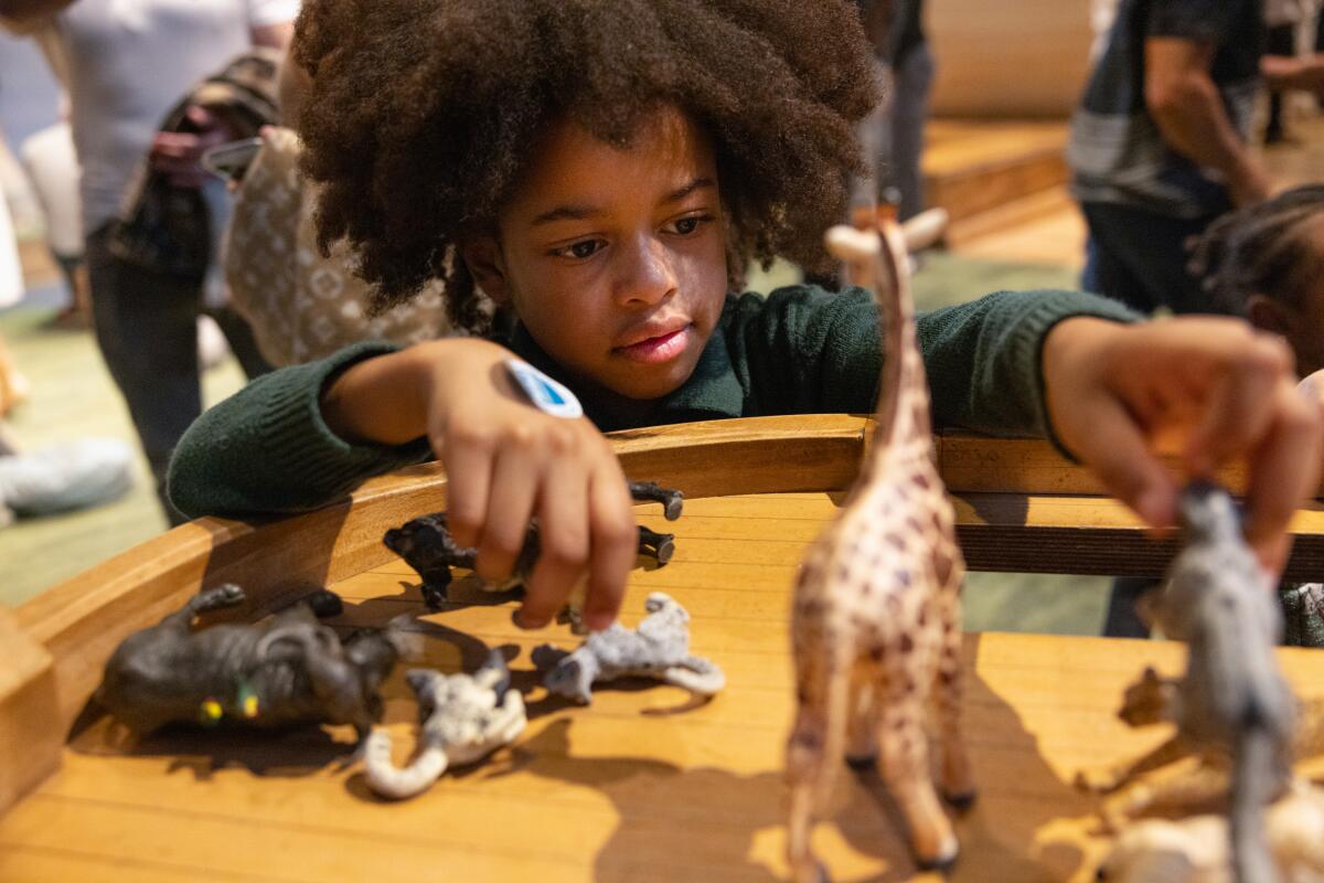 A child plays with the animal figurines on a miniature ship
