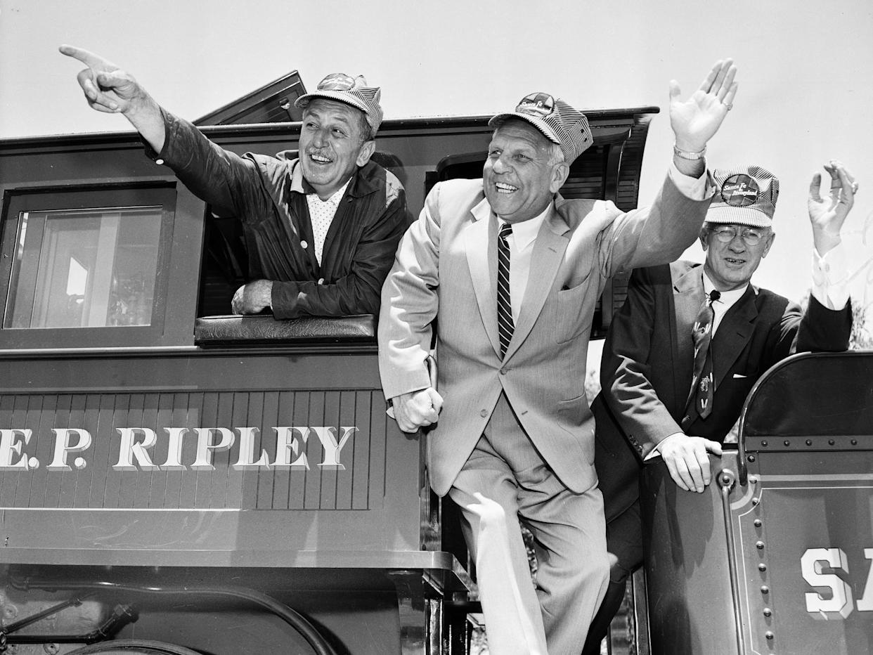 Walt Disney (left) waves on a train.
