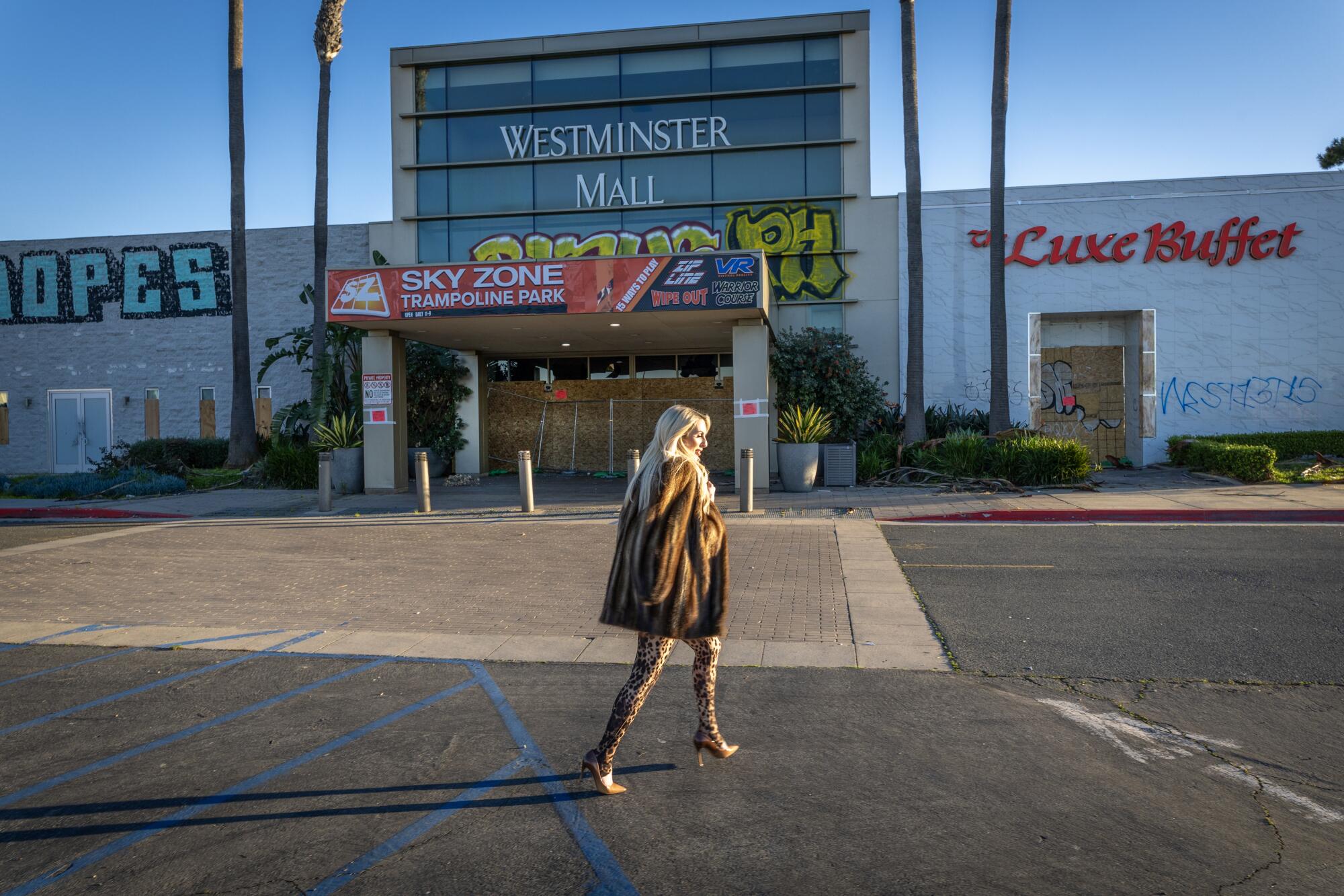 a woman walks in front of a shuttered mall