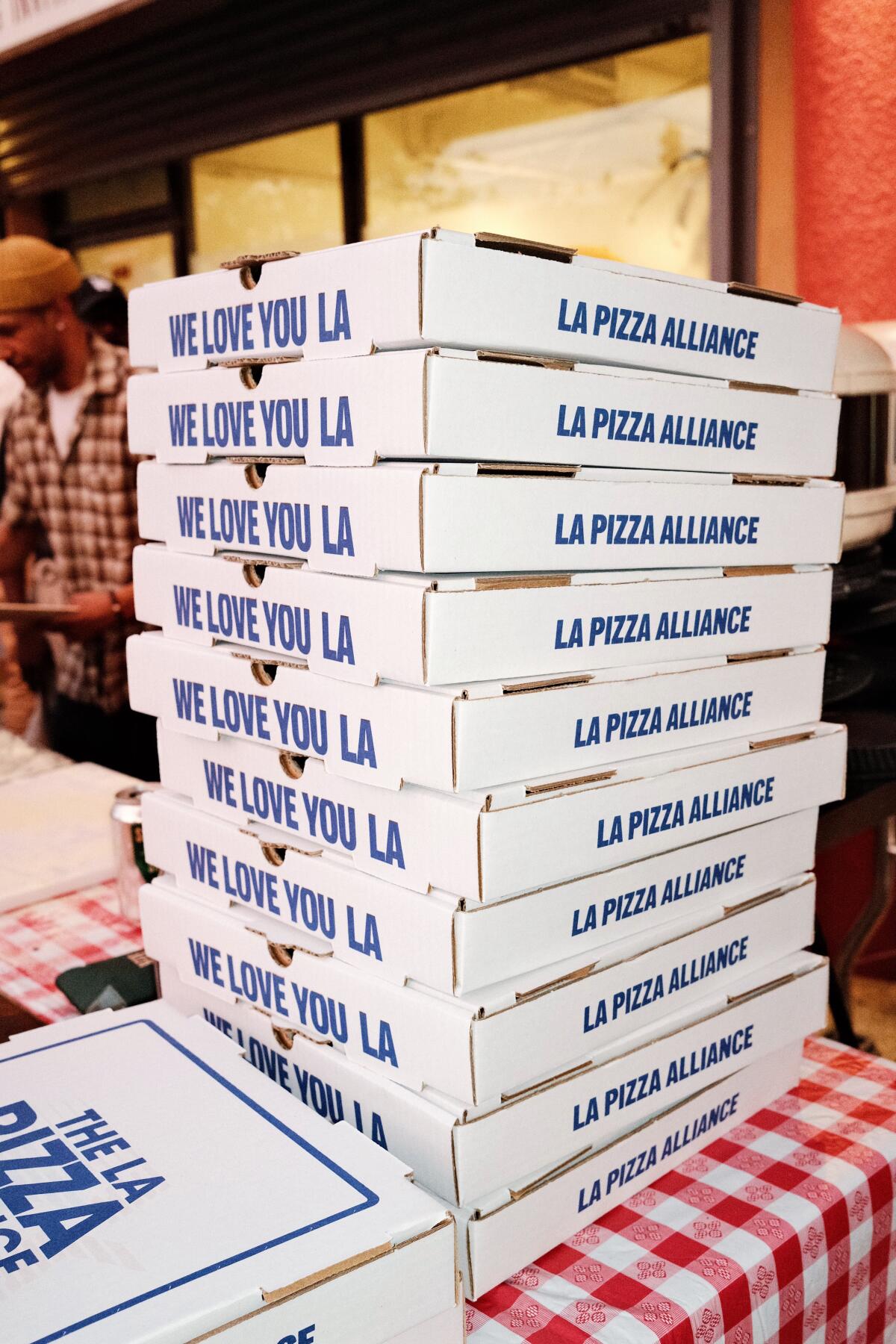 Stacks of cardboard pizza boxes that read, "WE LOVE YOU LA, LA PIZZA ALLIANCE"