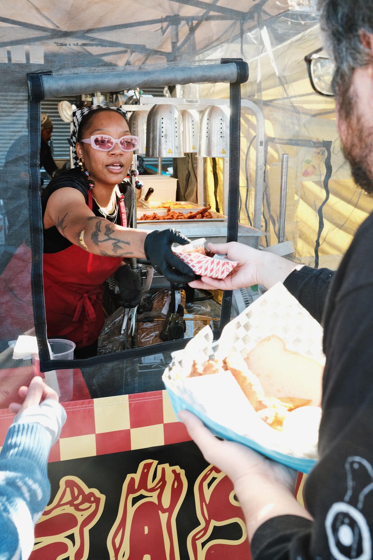 A woman hands a tray of food to a customer at a pickup window