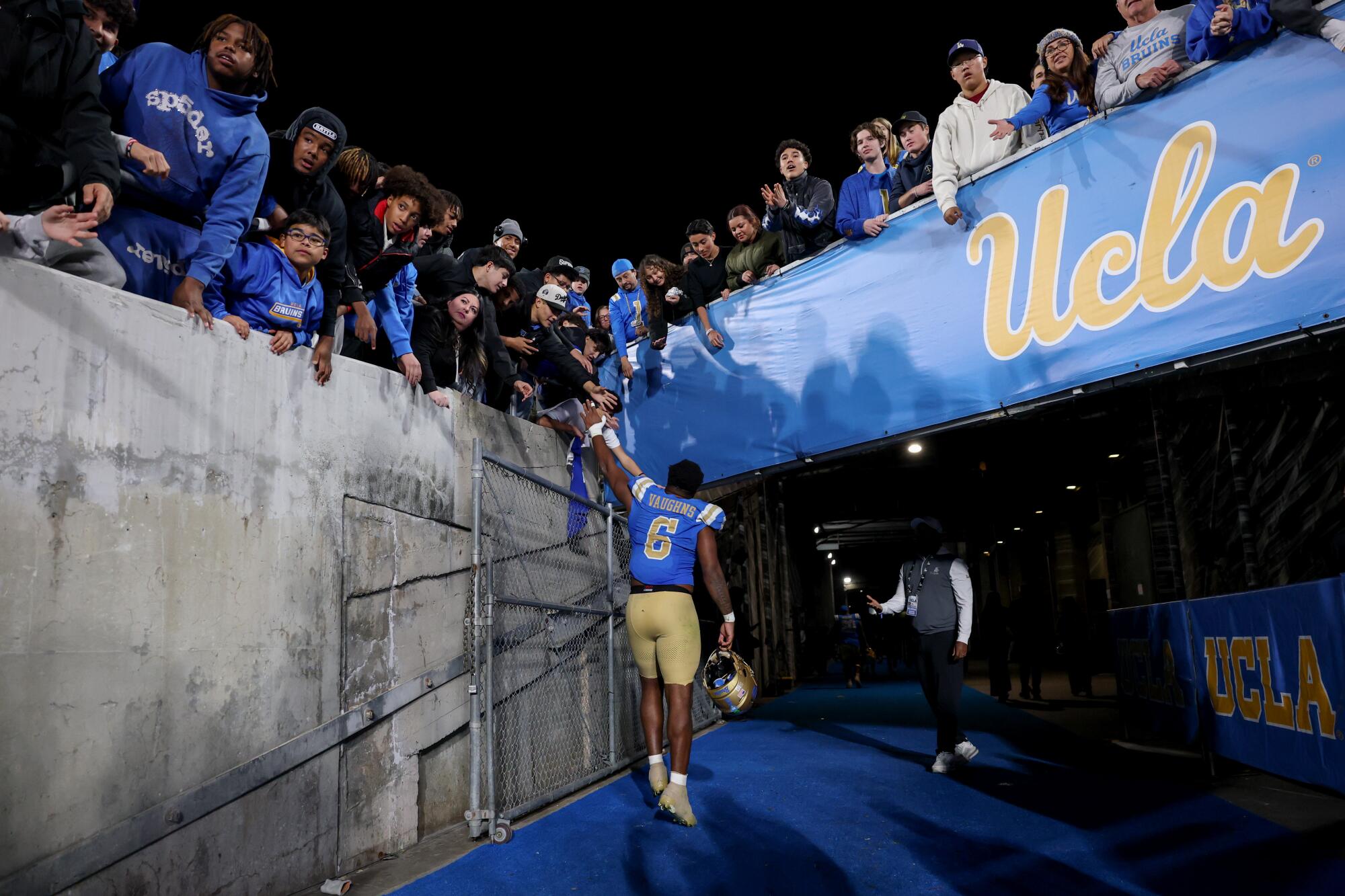 UCLA linebacker Jonjon Vaughns high-fives fans while leaving the field after a game against Washington at the Rose Bowl.