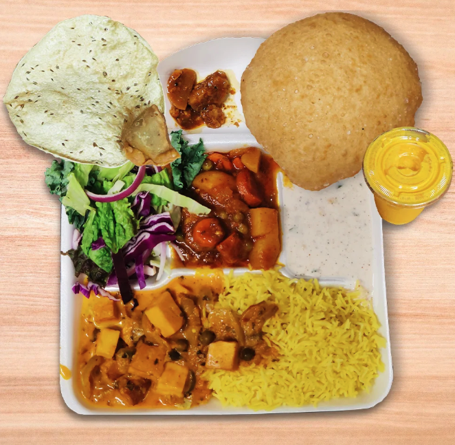 A square plate contains yellow rice, vegetables in an orange sauce, a green salad, and two pieces of puffed up naan
