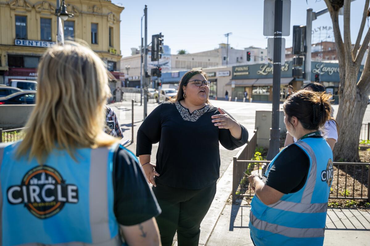 Three people converse outdoors.