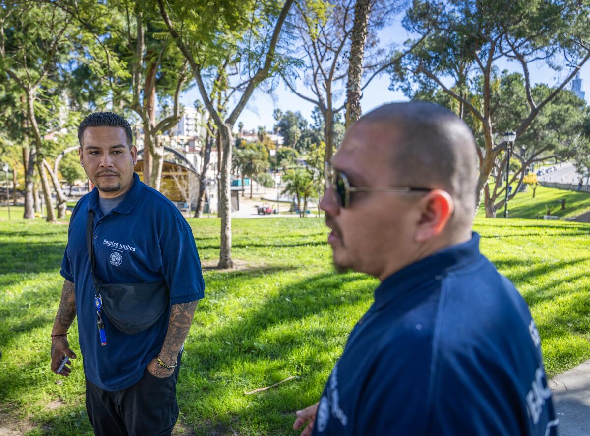 Two men stand next to a grassy area.