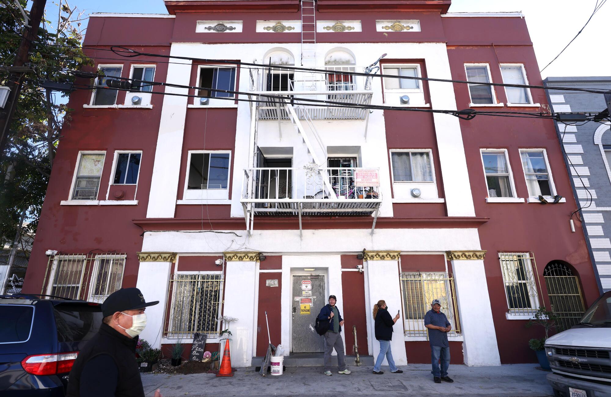 People walk outside a red and white apartment building.
