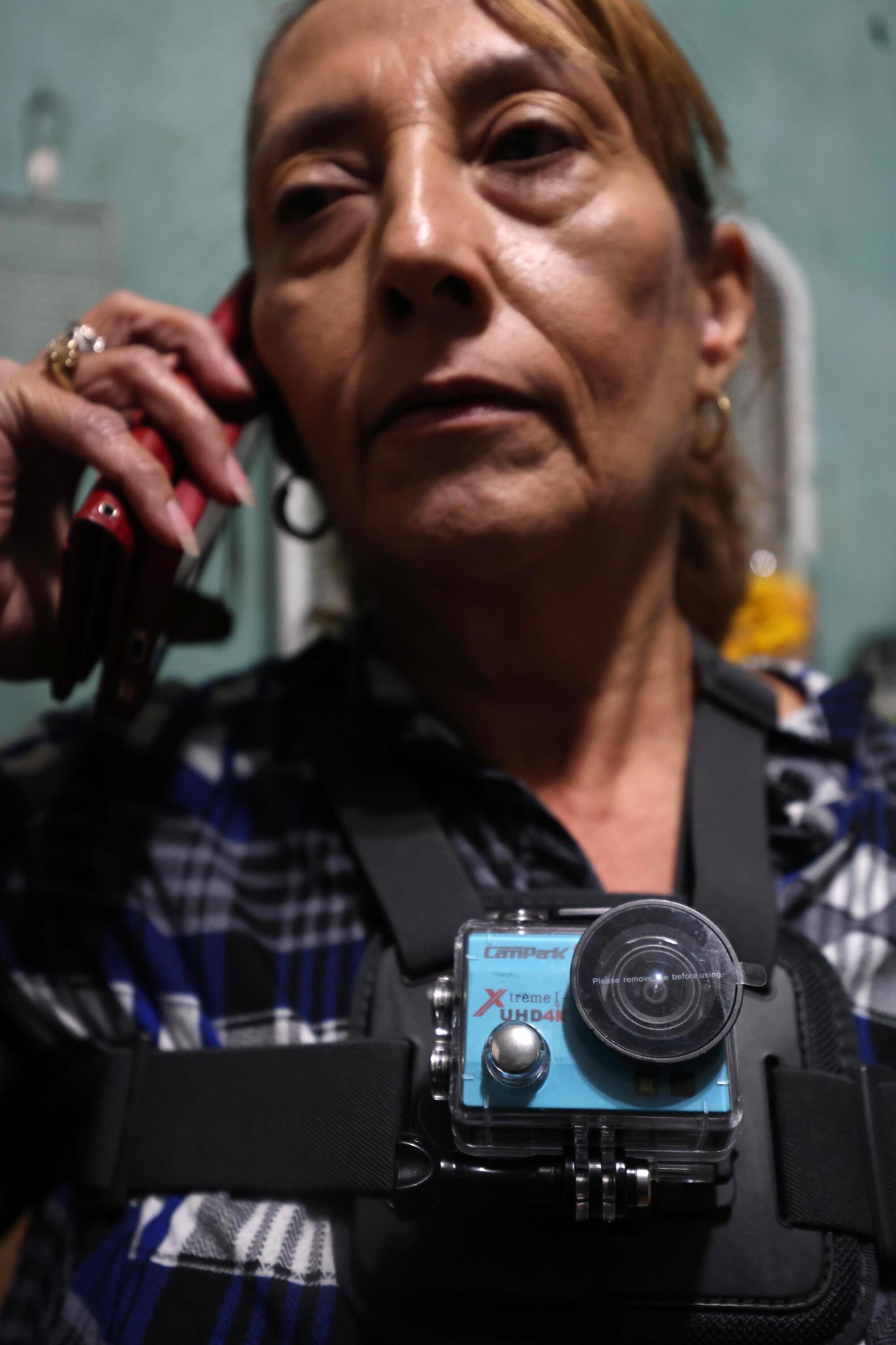 A woman wears a video camera on her neck.