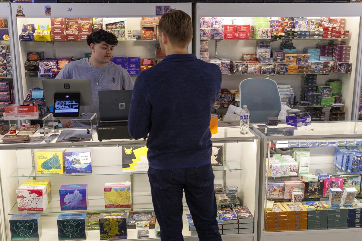 A team member assists a customer in purchasing Pokemon cards at RWT Collective.