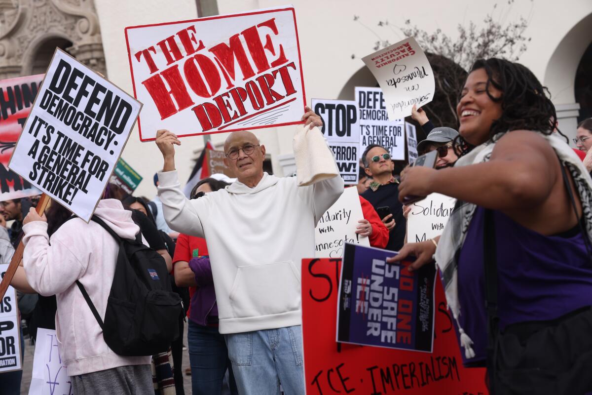 Approximately 200 people attend a rally holding signs protesting the actions of Immigration and Customs Enforcement (ICE)