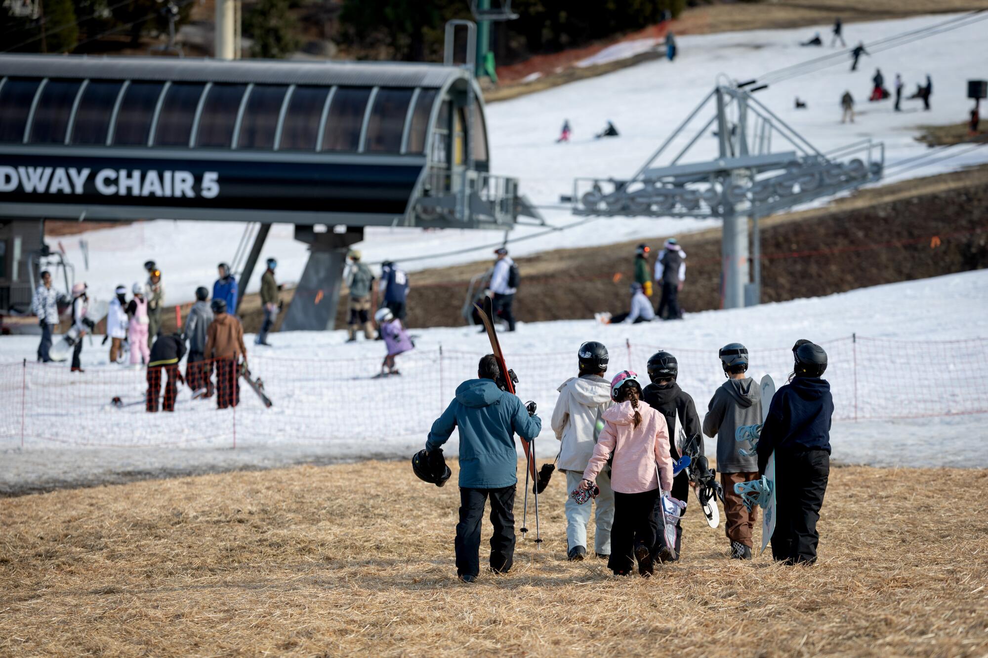 Skiers and snowboarders on snowless ground