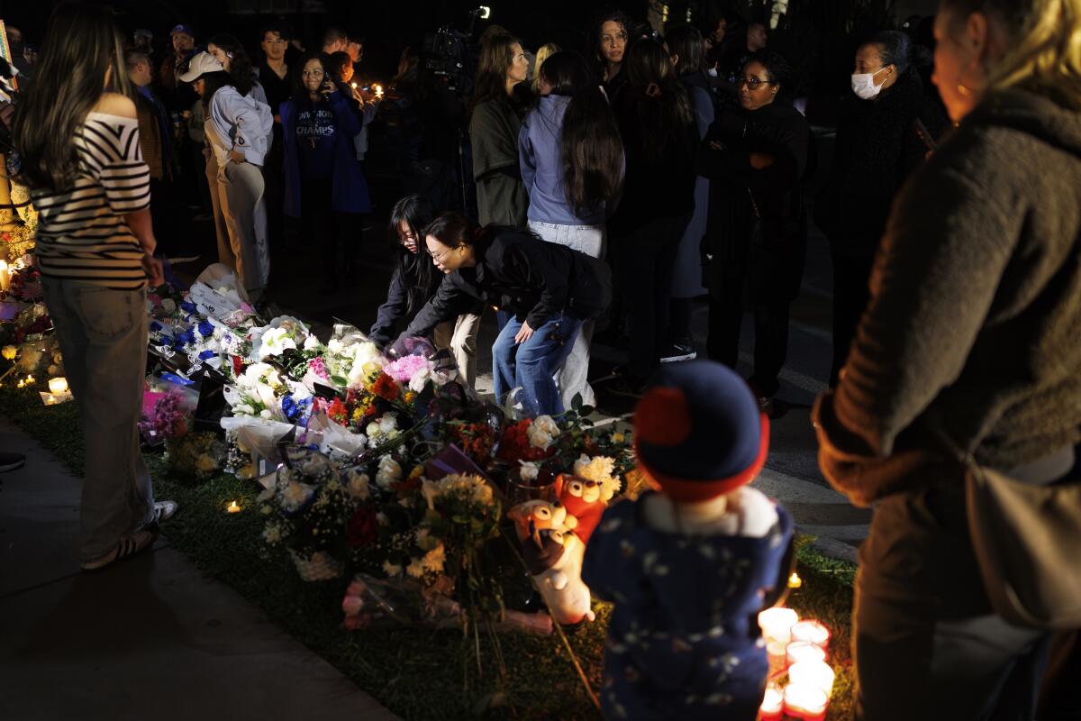 People gather around flowers and candles.