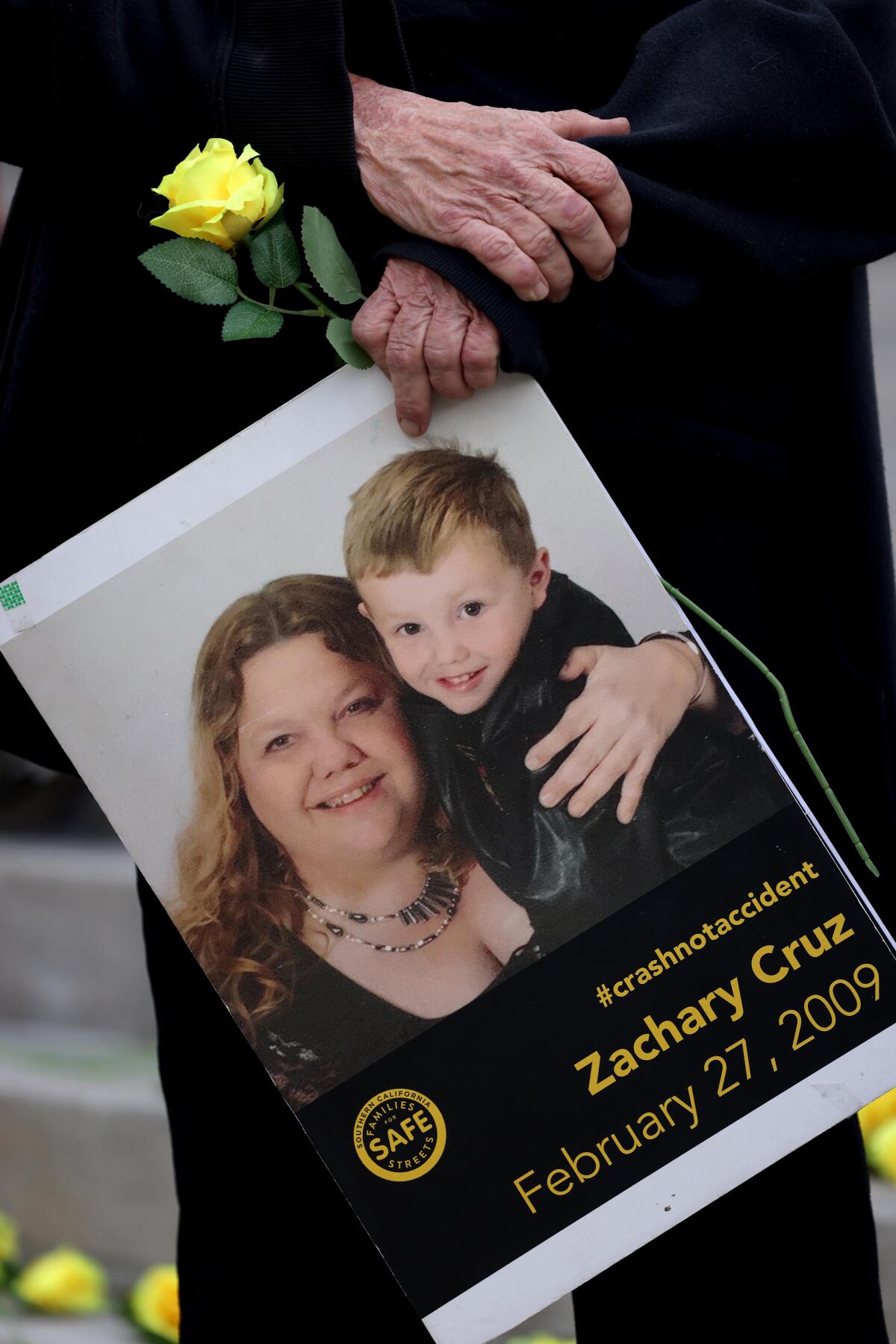 An older person's hands crossed and holding a large photo of a woman and a smiling young boy