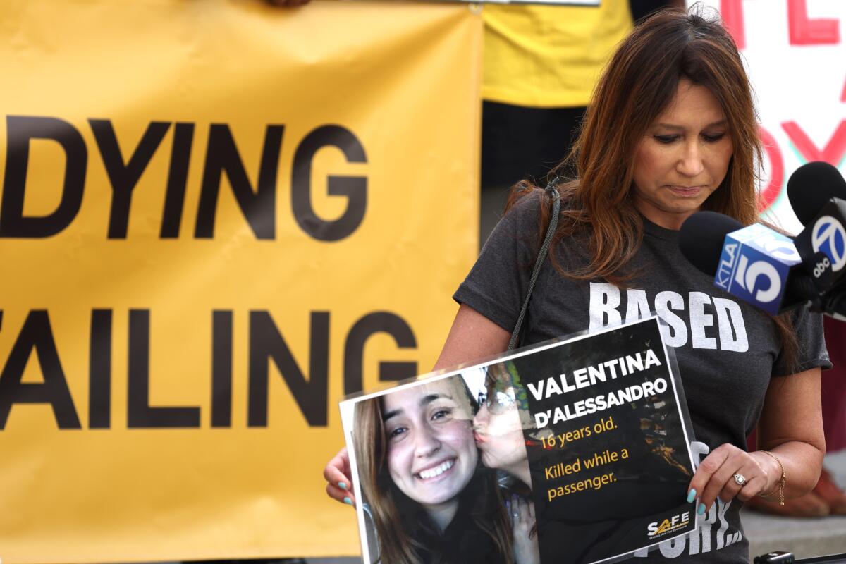 a woman looking downward while holding a poster showing a teen girl