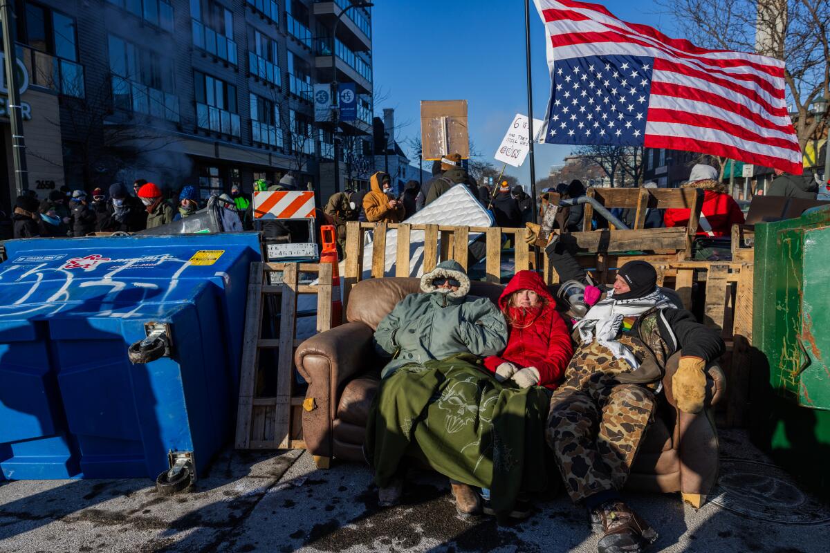 Residents sit near a makeshift blockade at the scene