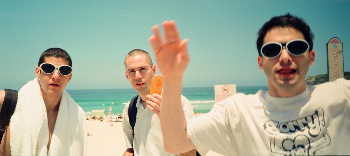 Three rappers cavort in front of the camera.