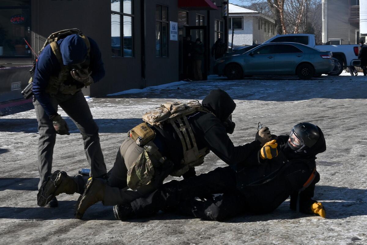 A federal agent tackles a man to the ground as another agent looks on